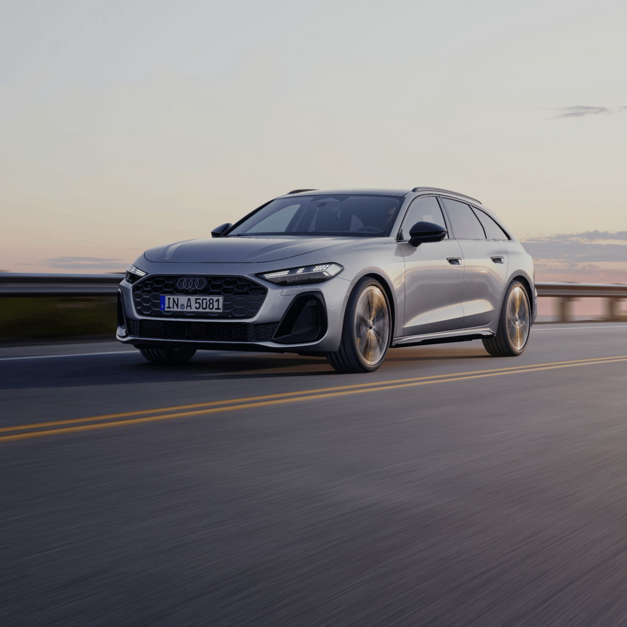 A silver Audi driving on a highway at dusk with motion blur.