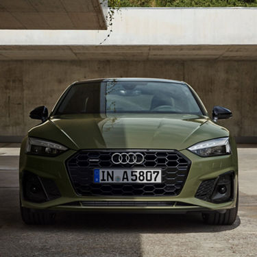 A green Audi car parked, facing forward, under a concrete structure.