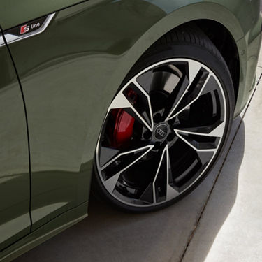 Close-up of a green Audi with S line badge focusing on its stylish alloy wheel and red brake calliper.