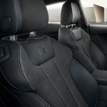 Car interior with black leather sport seats featuring an embossed 'S' logo.