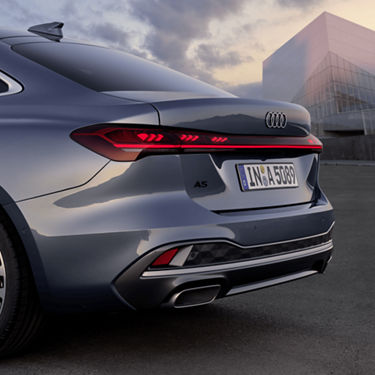 Rear view of a silver Audi A5 Saloon with illuminated taillights, parked outside.