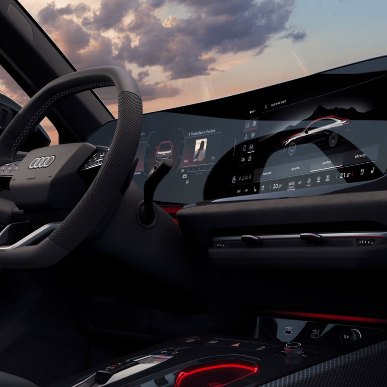 Interior of an Audi car with digital dashboard and touch screens at dusk.