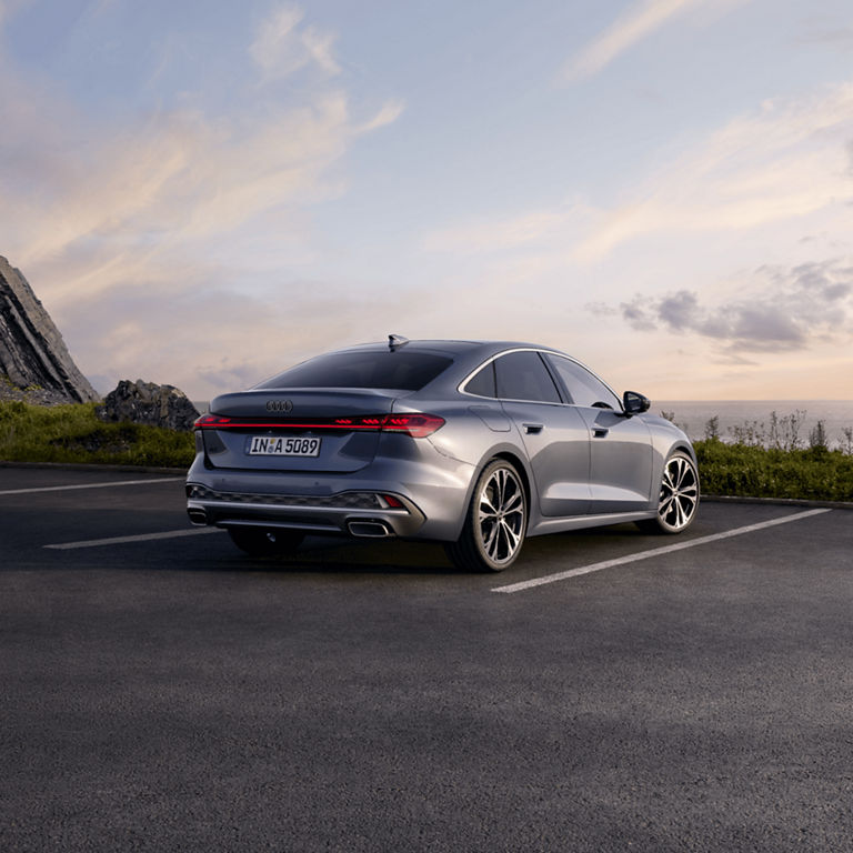 A silver Audi A5 Saloon on a coastal road at dusk with a clear sky.