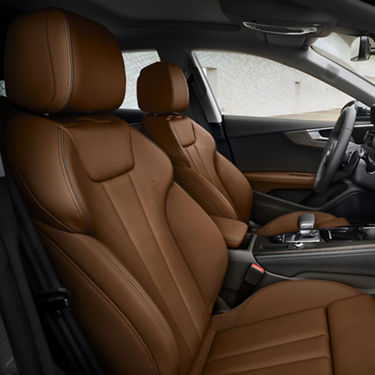 Interior of a car with brown leather seats, center console, and steering wheel.
