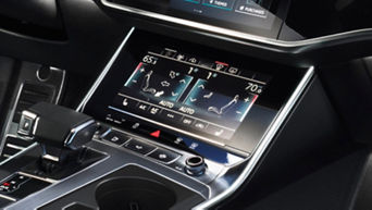 Car's center console with touchscreen climate control system and gear shifter.