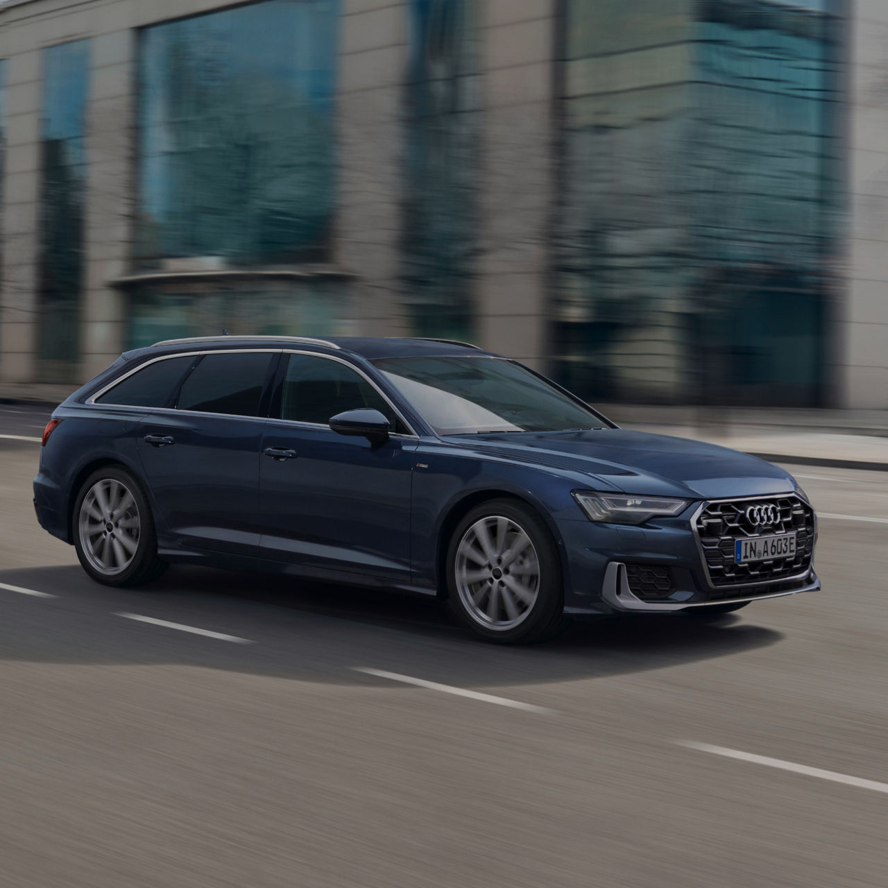 A blue Audi in motion on a city street with blurred background.