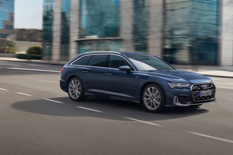 A blue car driving on an urban road with blurred background.