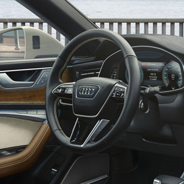 Interior view of a car focusing on the steering wheel and digital dashboard.