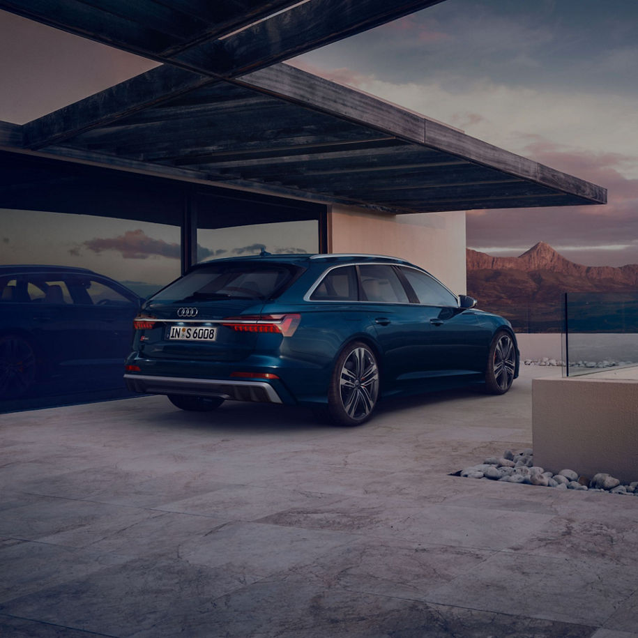 Blue car parked in a modern carport with mountains in the background at dusk.