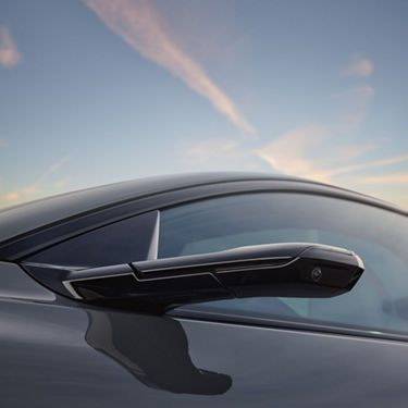Close-up of a car's side mirror against a blurred sky background.
