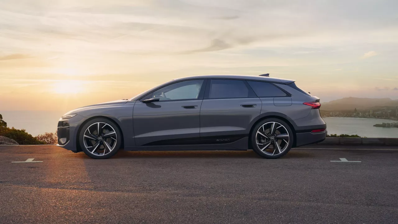 An electric car parked overlooking a coastal city at sunset.