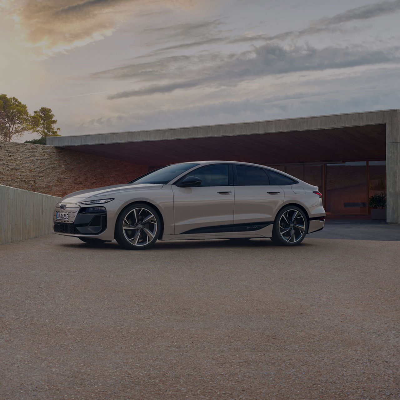 Sedan parked in front of a modern building at dusk.