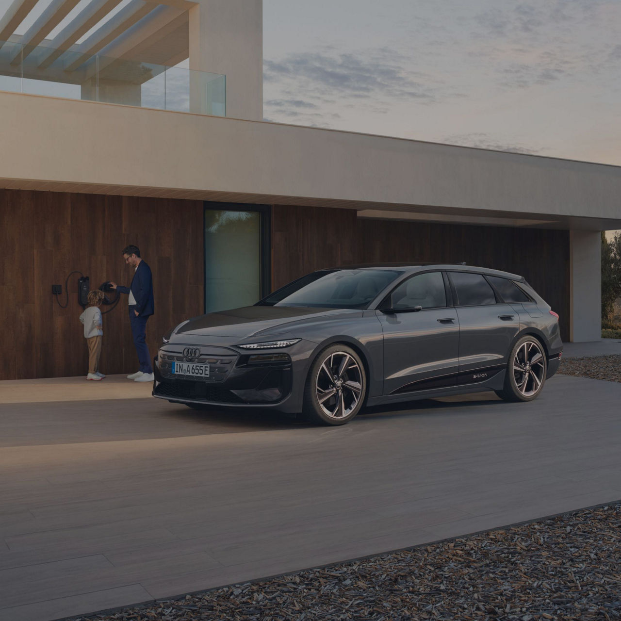 Car parked outside a modern house with two individuals by the doorway.