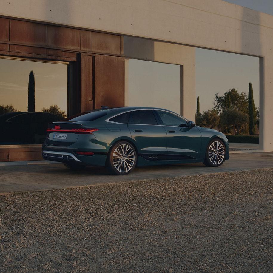 A dark colour sedan parked outside a modern building at dusk.