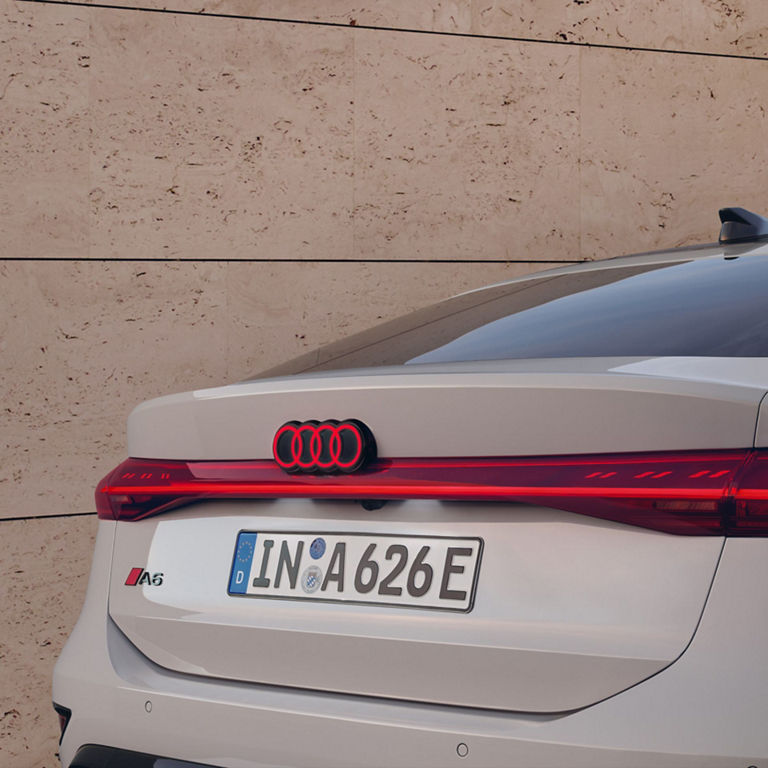 Rear view of a white Audi A6 with distinctive taillights and a license plate.