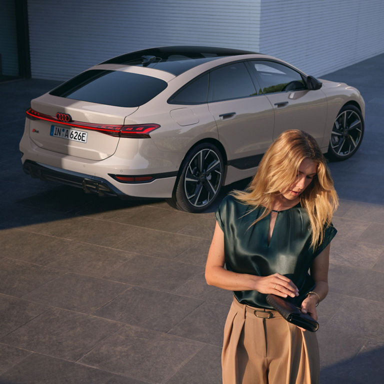 White Audi car parked outside a house, person in foreground.