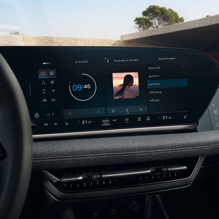 Car dashboard with large touchscreen displaying music, clock, and drive mode settings.