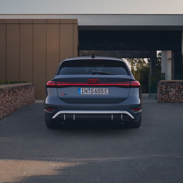 Rear view of Audi S6 Avant e-tron parked in a driveway displaying LED taillights and dual exhausts.