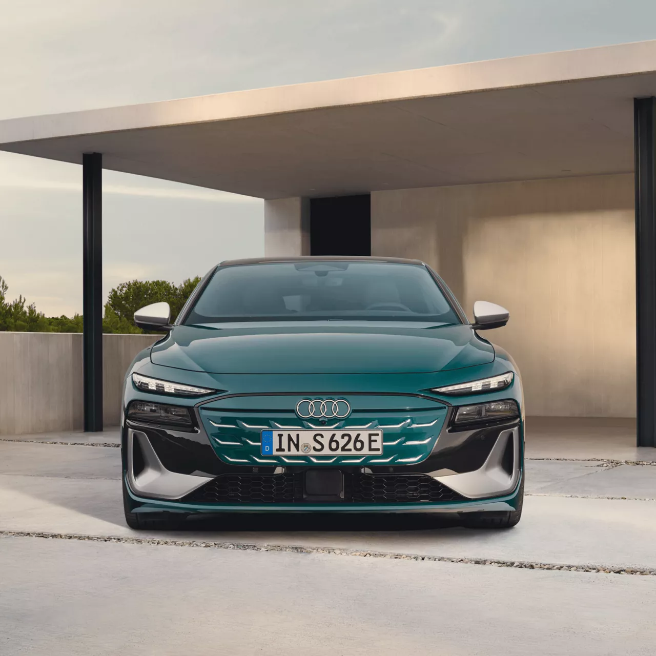 Green Audi car parked in front of modern architecture, under a concrete overhang.