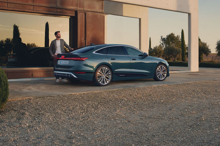 Sedan parked outside a modern house at dusk.