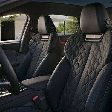 Car interior with elegant black leather seats and red trim.