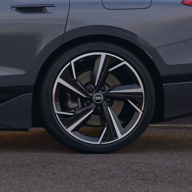 Close-up of a car's wheel with a distinctive Audi logo on the hubcap.