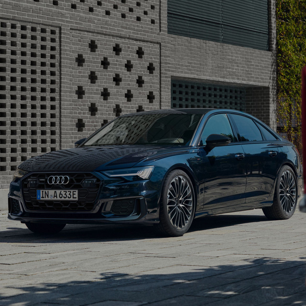 A blue Audi sedan parked by a brick building.