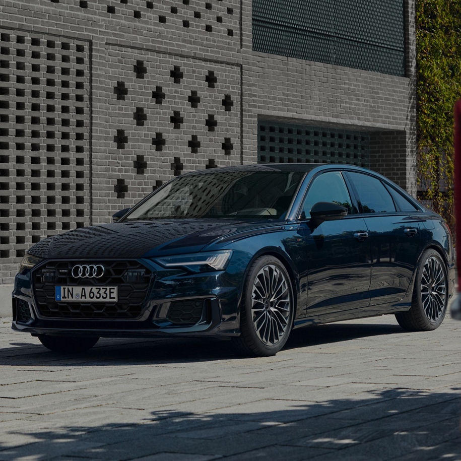 A blue Audi sedan parked by a brick building.