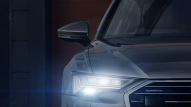 Close-up of car's front with LED headlights and side mirror.