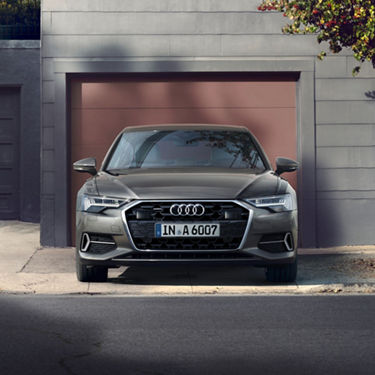 Car parked in front of a garage with a partially shaded facade.