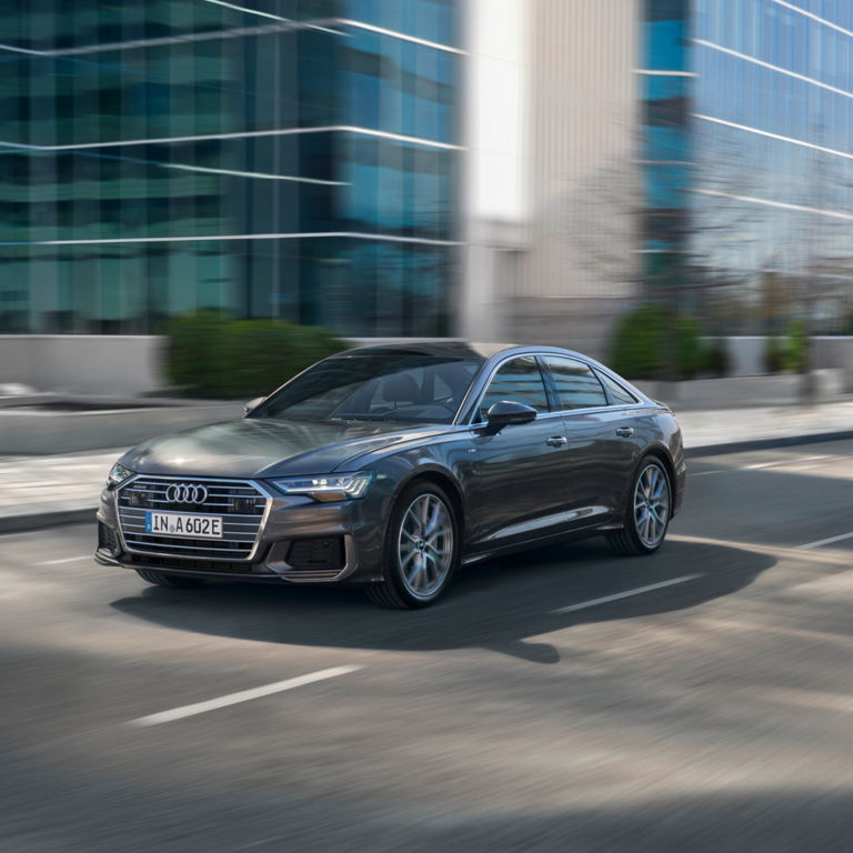 Sedan car in motion on a city street with blurred background.