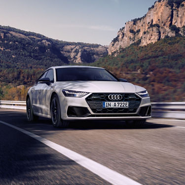 Car driving on a road with mountainous backdrop.
