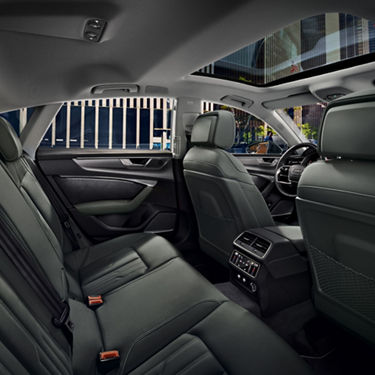 Interior view of a modern car's backseat area, showcasing leather seats and a sleek dashboard.