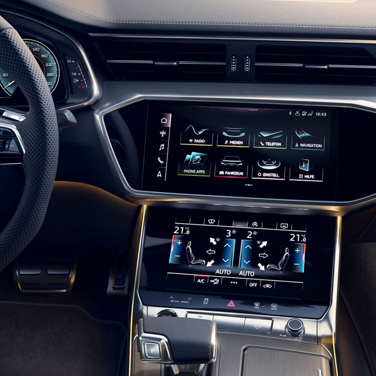 Car interior with steering wheel, digital displays, and center console controls.