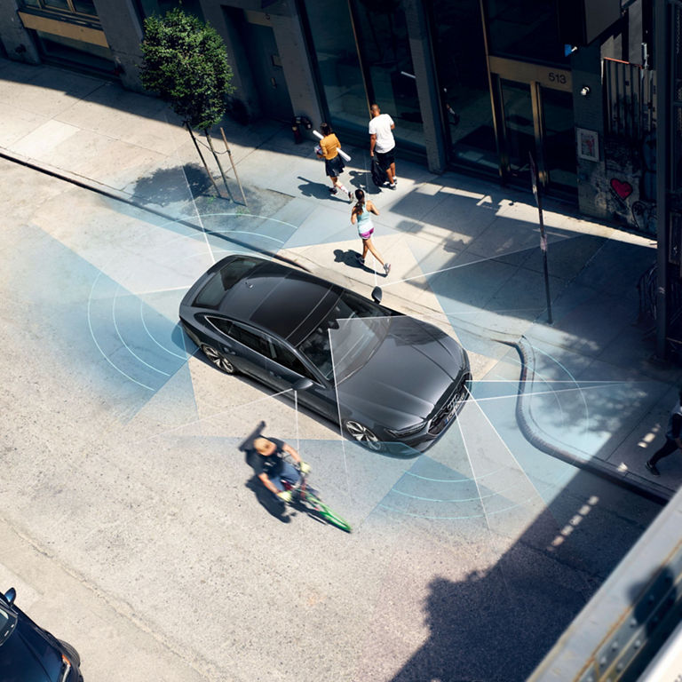 Aerial view of a black car with sensor waves illustrating autonomous driving, amidst pedestrians and cyclists.