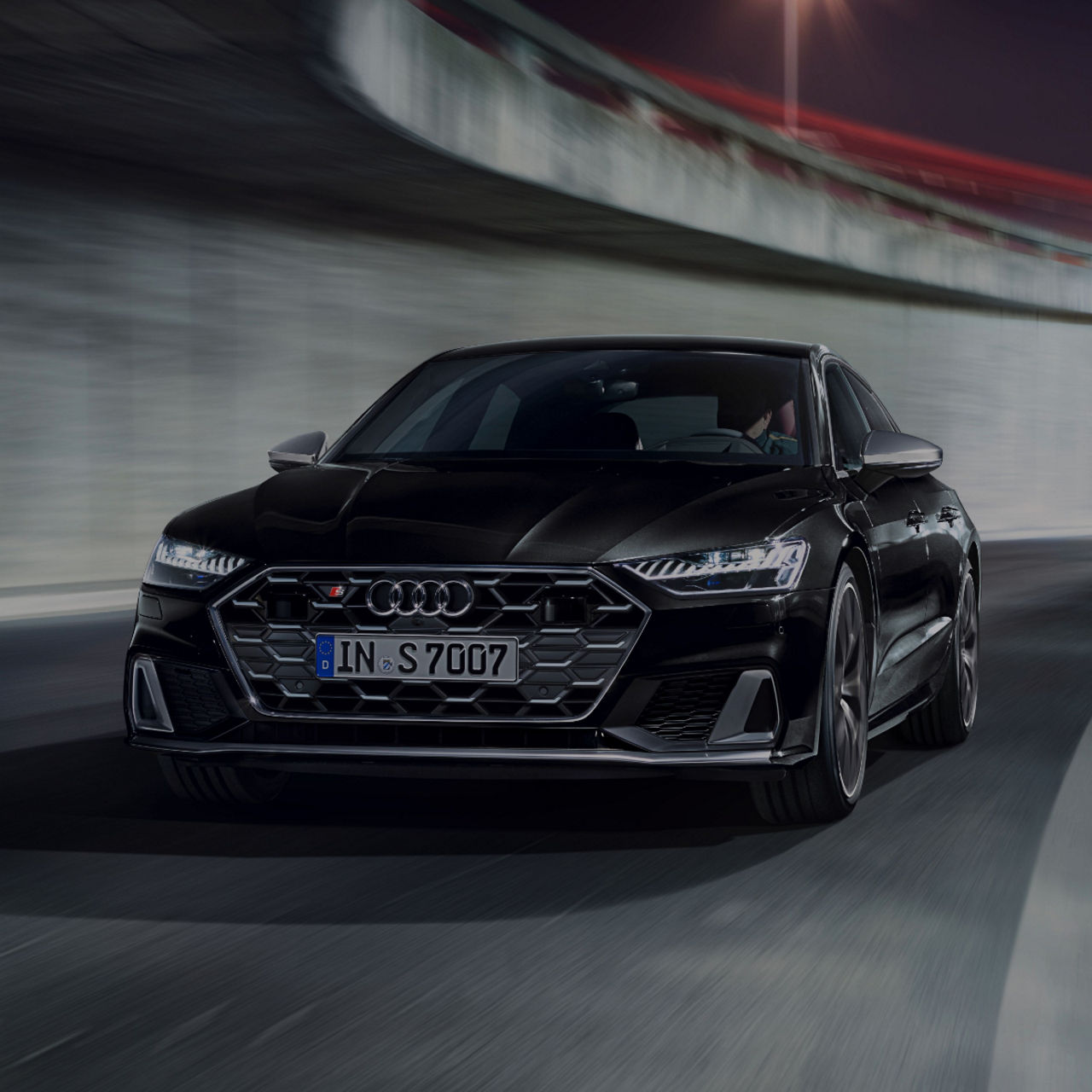 A black Audi S7 Sportback in motion on a blurred urban road.