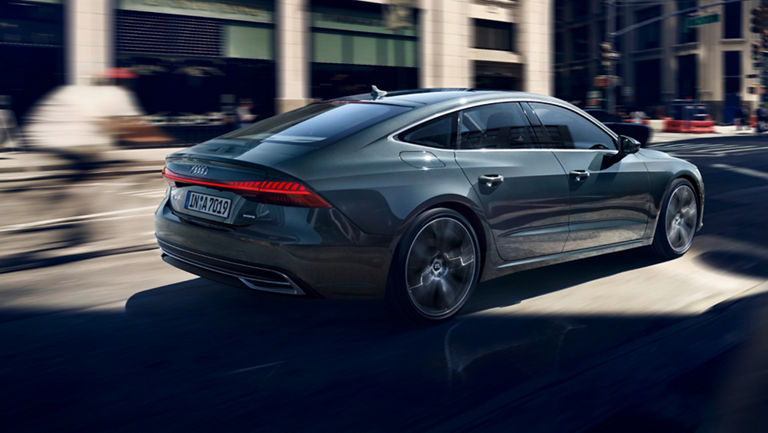 Audi sedan in motion on a city street, exhibiting speed with a blurred background.