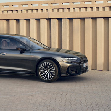 Sedan parked near a concrete wall, showcasing shiny rims and elegant design.