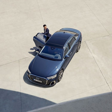Aerial view of a blue sedan with an open driver's door.