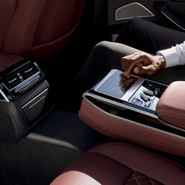 Person using a touchscreen device in a modern car's luxury interior.