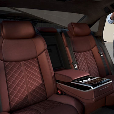 Car interior showing two high-end brown leather seats with quilted patterns.