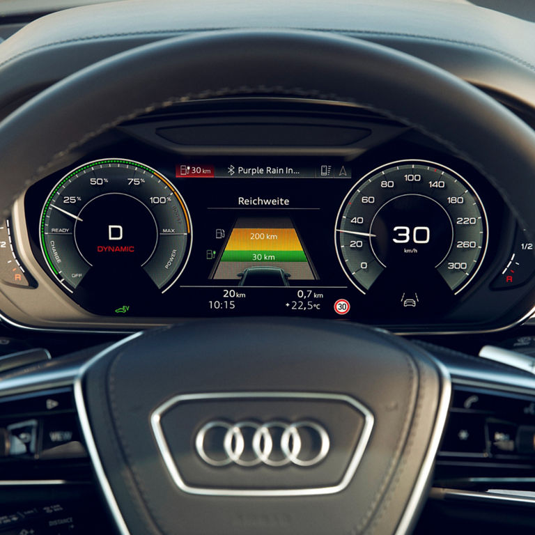 Driver's view of an Audi's steering wheel and digital dashboard display showing speed and music track.