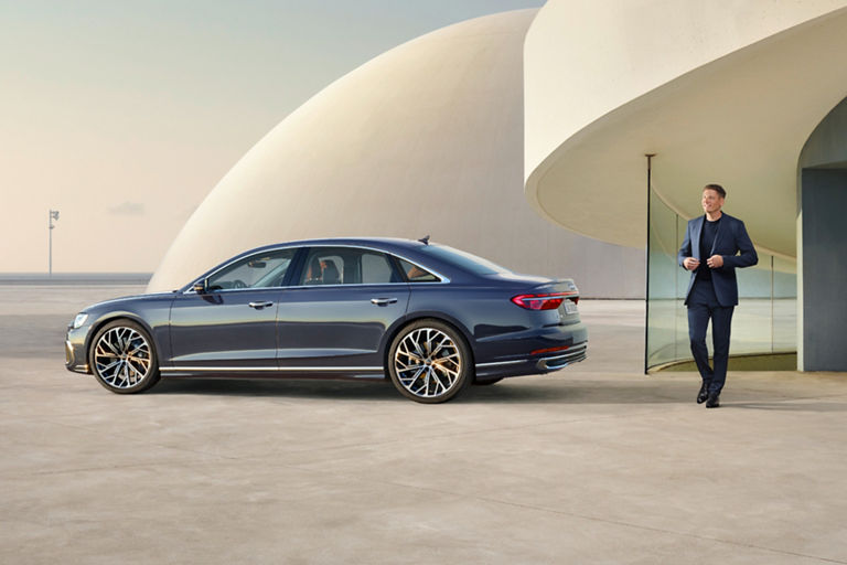 A car parked outside a modern building with a person standing nearby.