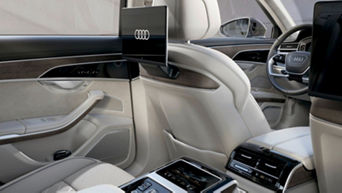 Car interior with modern dashboard, cream leather seats, and Audi logo on screen.