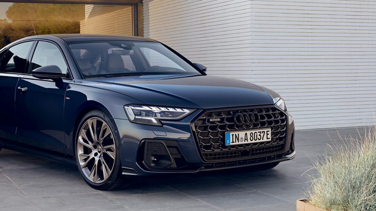 Blue Audi sedan car parked beside a modern building.