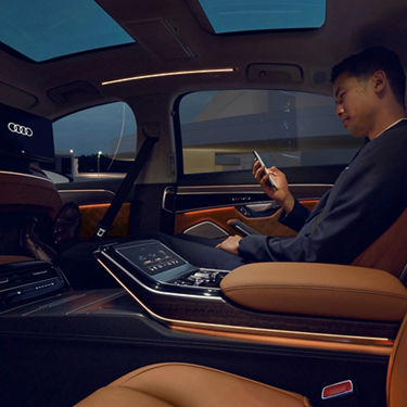 A person sitting in a luxurious car interior, interacting with a smartphone.