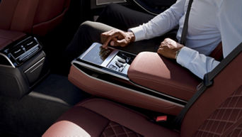 Person using a touchscreen display in a car's rear seat.