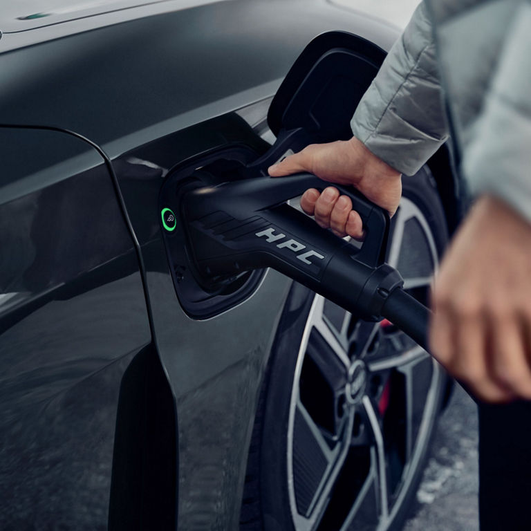 Person plugging an electric vehicle into a charging station.