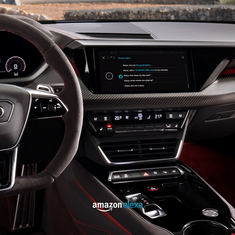 Interior of a car featuring steering wheel with an Audi logo and Alexa integration on dashboard screens.