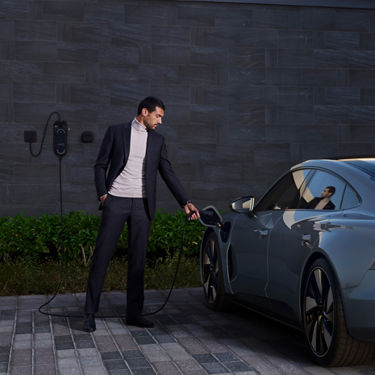 Person in a suit charging an electric car.
